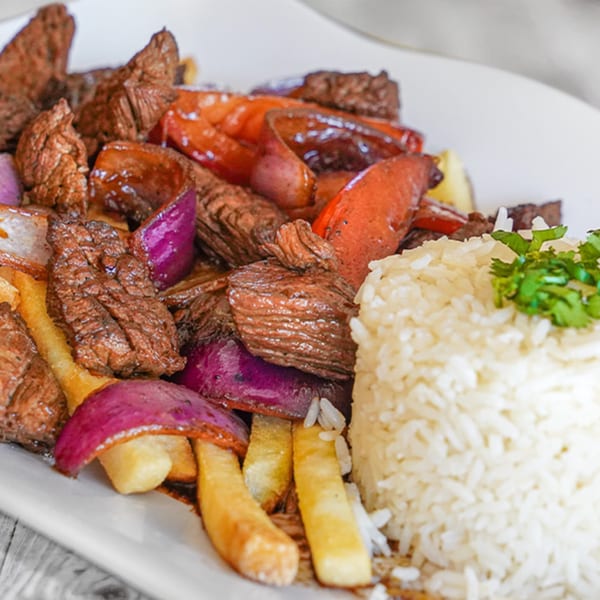 Peruvian Lomo Saltado with beef, red onions, tomatoes, french fries, and white rice.