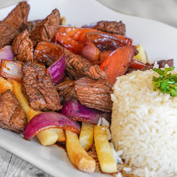 Peruvian Lomo Saltado with beef, red onions, tomatoes, french fries, and white rice.