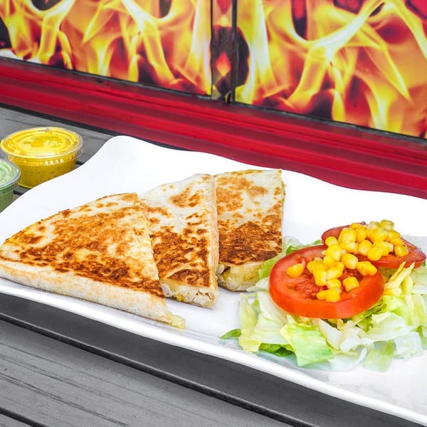 Three golden-brown quesadilla slices with a side salad of lettuce, tomato, and corn, with sauces.