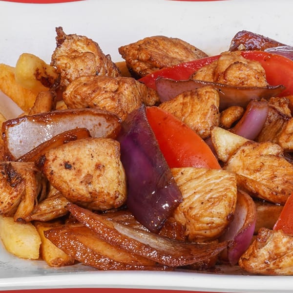 Peruvian Lomo Saltado with chicken, red onions, red bell peppers, and french fries.