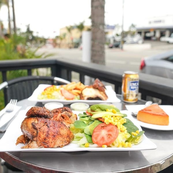 Peruvian rotisserie chicken with salad, fries, and flan on an outdoor patio table.