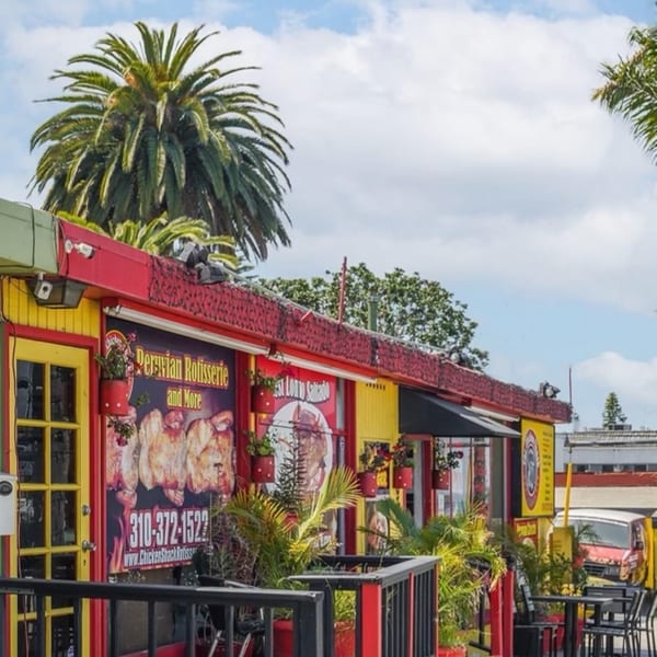 The Chicken Shack's vibrant yellow and red exterior with Peruvian rotisserie chicken signage and outdoor seating.